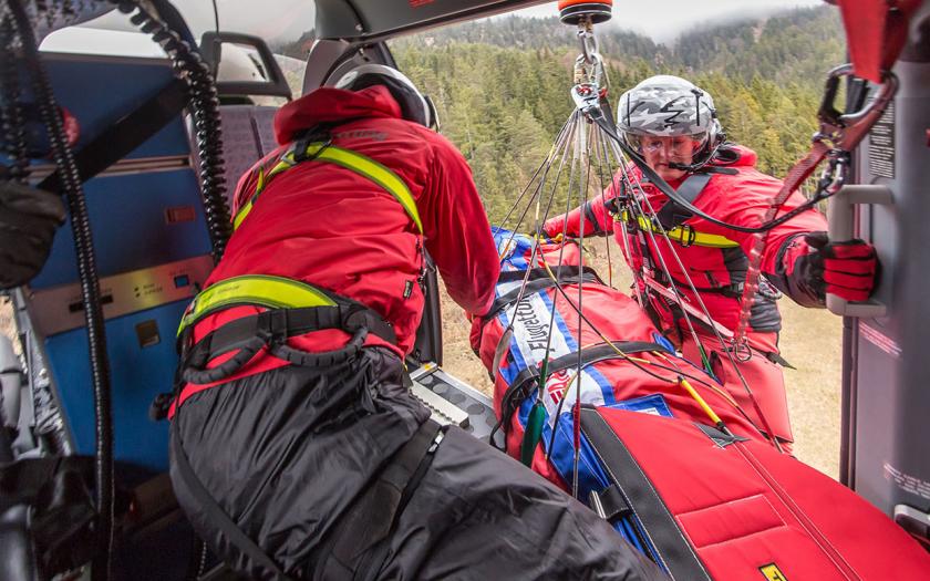 Patient wird im Bergesack an der Rettungswinde hängend in den Hubschrauber verladen.