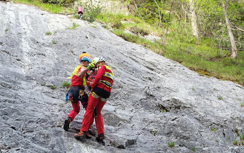 Zwei Flugretter hängen an der Rettungswinde an einem Berghang