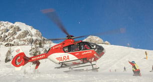 Ein Hubschrauber landet am schneebedeckten Hang