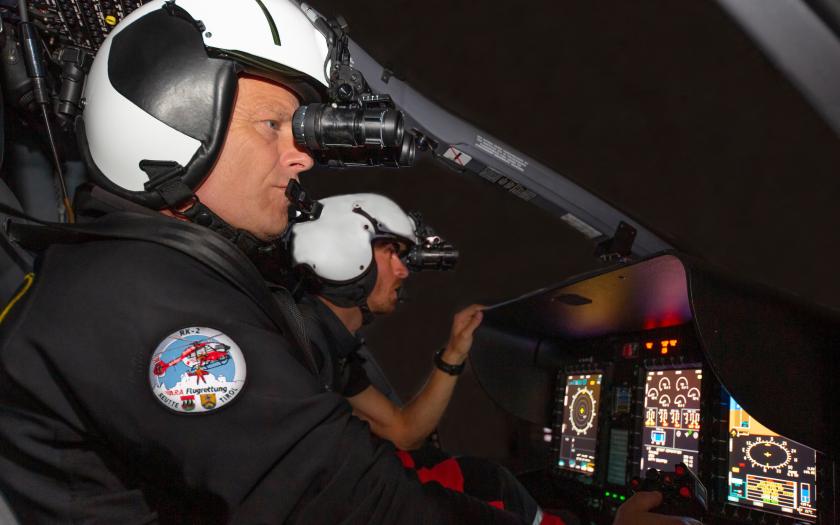 Zwei Hubschrauberpiloten sitzen im Cockpit und tragen eine Nachtsichtbrille